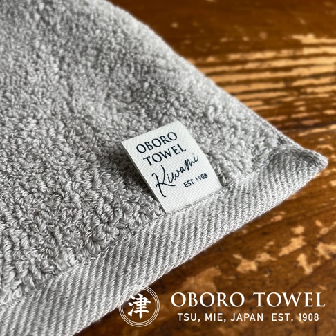 灰色細纖浴巾，質地柔軟，帶有「OBORO TOWEL KIWAMI EST. 1908」標籤。