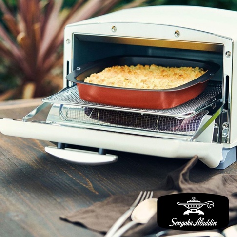 復古多用途烤箱內有一個紅色的烤盤，裡面裝滿了金黃色的食物，烤箱門打開，露出烤箱內部和下方放置的烤網。