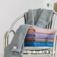 五色今治毛巾疊放在金屬椅上，包括灰藍、粉紅、紫、灰棕與寶藍色，毛巾表面有著細緻的鱗紋織紋。