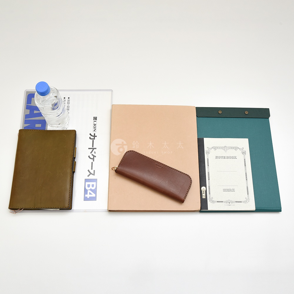 皮革筆記本、棕色皮革筆袋、淺棕色資料夾、綠色資料夾及一瓶水。