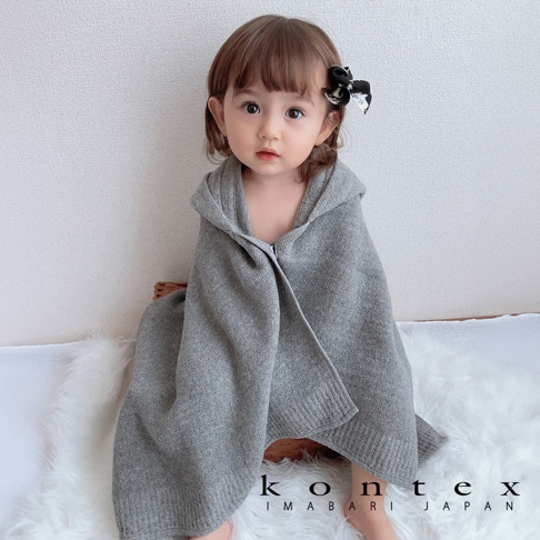 一名嬰兒身著灰色針織連帽浴巾，浴巾採用純棉材質，帶有羅紋邊緣。