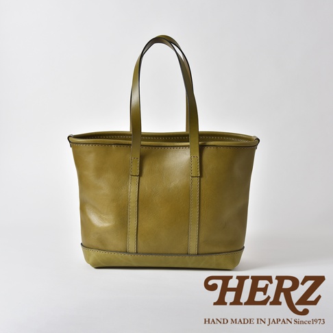 一款橄欖綠色的皮革托特包，具有兩個提把，簡約的設計，底部有加固皮革，整體呈現職人手作質感。