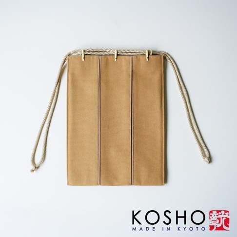 京都KOSHO出品的ougi帆布信玄袋，以素雅的淺棕色帆布製成，設計簡約且具有直條縫線細節，搭配米白色繩索作為束口背帶，展現傳統工藝與現代簡約風格的結合，呈現正視的拍攝角度。