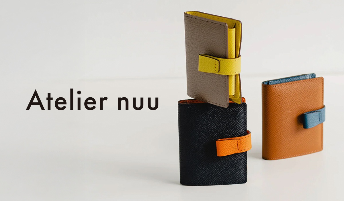Atelier nuu 品牌字樣旁，堆疊著三個色彩鮮豔的皮革長夾。