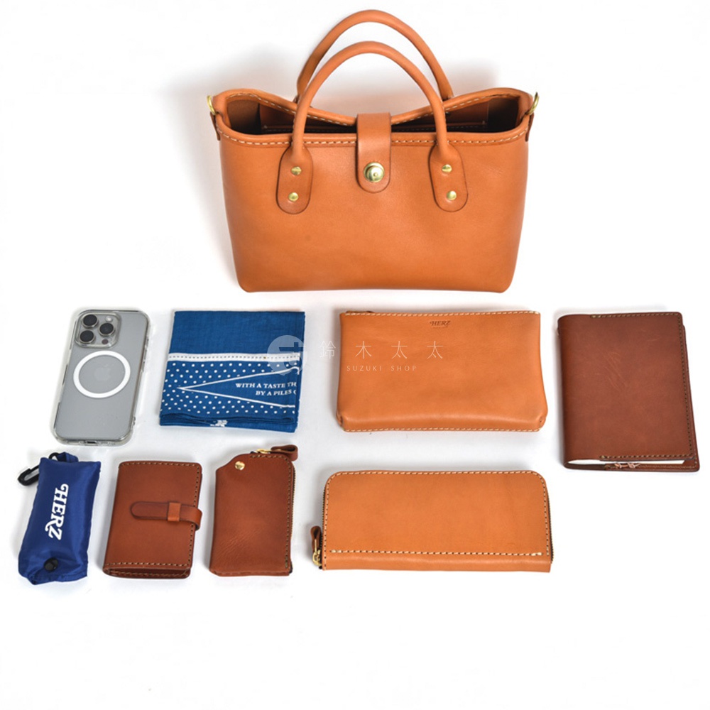 職人手作皮革迷你托特包，搭配手機、藍色印花手帕、橘色皮革長夾、橘色皮革零錢包、橘色皮革卡夾、橘色皮革鑰匙包，以及藍色收納袋。