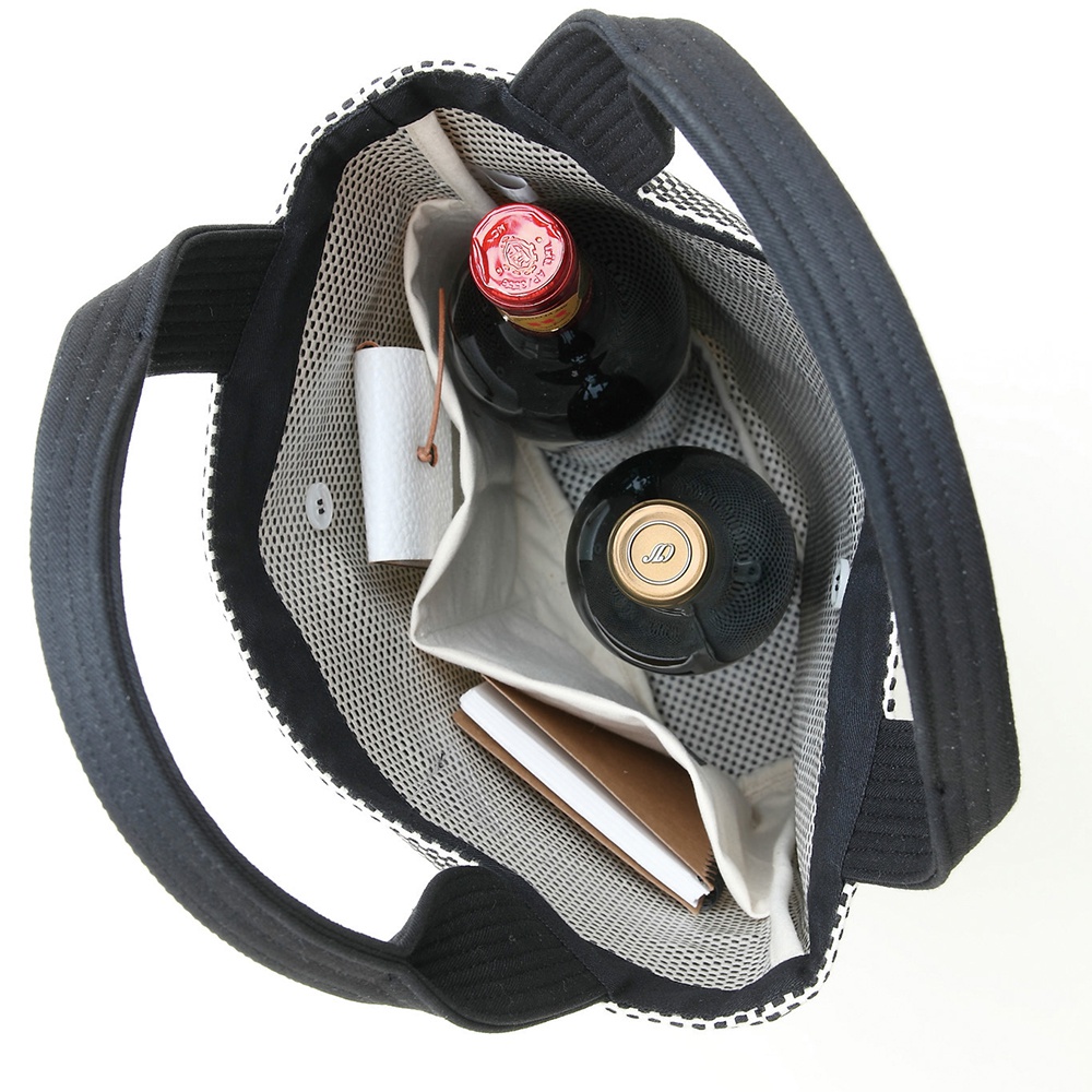 三河木綿刺子織直式收納托特包，黑色帆布提把，內部有網狀隔層，放置兩瓶黑色瓶身的酒、一個白色小筒狀物體和一本棕色封面的筆記本。