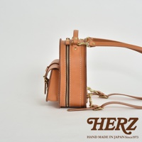 職人手作皮革迷你後背包，展示側邊視角，皮革顏色為棕褐色，搭配黃銅色拉鍊與扣環，結構紮實，設計簡約。