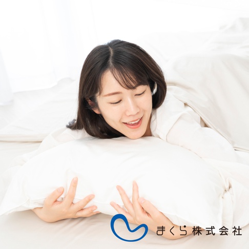 一位女士擁抱著一個白色枕頭，枕頭套看起來是棉絲混紡材質。