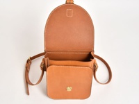 職人手作皮革翻蓋迷你單肩包 (CP-6)，採用天然棕色皮革，結構清晰，縫線細緻。包包的翻蓋向上打開，露出內部空間，前方有一個小巧的鎖扣。附有可調節的皮革肩帶。