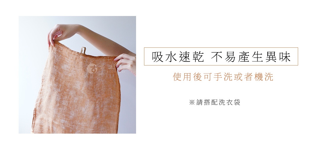 一隻手拿著一條橘棕色、織紋明顯的三層蚊帳棉織廚房拭巾，拭巾上有一個圓形標誌。