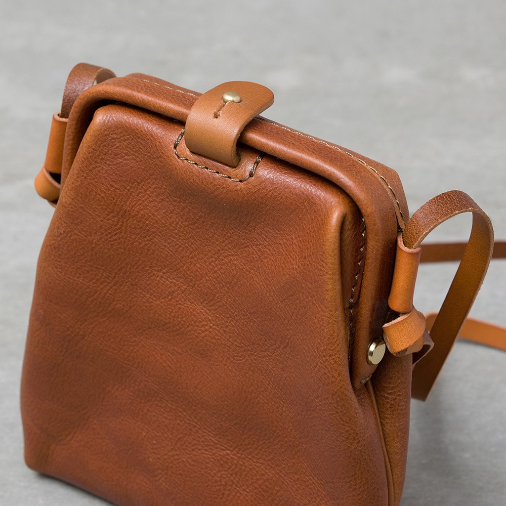 職人手作皮革Organ迷你杜勒斯側背包，採用棕色皮革製成，設有金色金屬扣和皮革束帶。