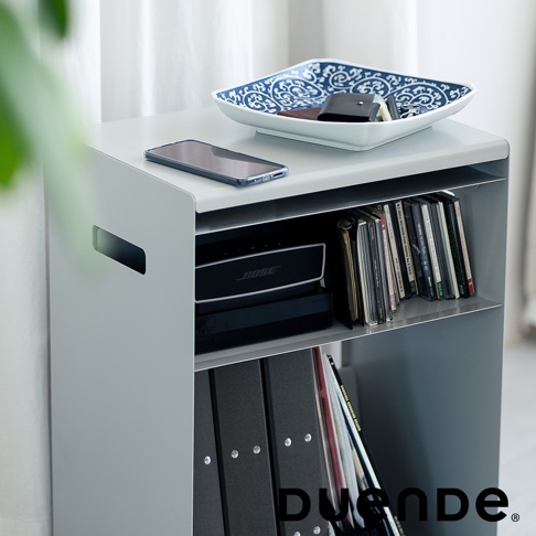 灰白色鋼製收納推車，頂部擺放有手機與藍紋裝飾碗，碗內有錢包與鑰匙。推車中間層架有BOSE音響、CD光碟片，下方則有黑色文件夾與書籍。