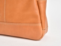 一側特寫職人手作皮革直式肩背托特包，採用天然棕褐色皮革，縫線清晰，質感細膩。