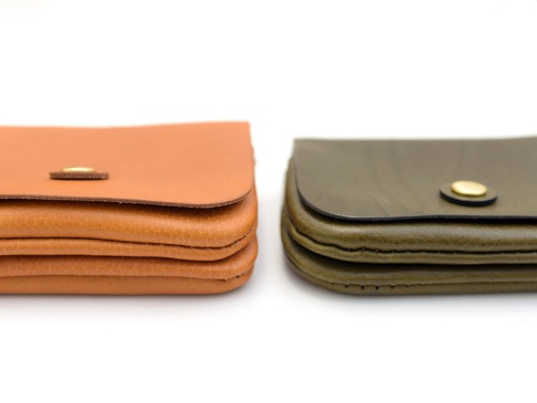 兩款職人手作皮革長夾，一款為棕褐色，另一款為墨綠色，皆採用皮革材質，並配有金色按扣，設計簡潔實用。