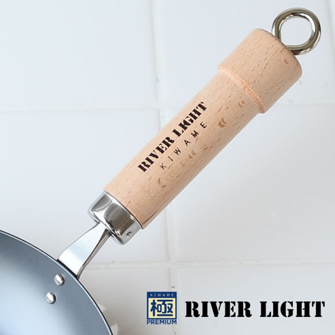 極PREMIUM 不易生鏽平底鍋，特寫木質手柄，印有「RIVER LIGHT KIWAME」字樣，手柄末端有金屬掛環，鍋身為黑色金屬材質。