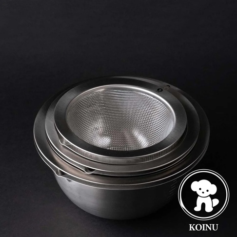 銀色不鏽鋼濾水網置於帶有刻度的大型不鏽鋼料理盆上，兩者皆為金屬材質，呈現簡潔的設計。