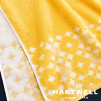 今治和風傳統紋樣言織浴巾，展示了鮮明的黃色與白色交織的織物，帶有重複的幾何花卉圖案，觸感柔軟，展現出日式傳統美學。