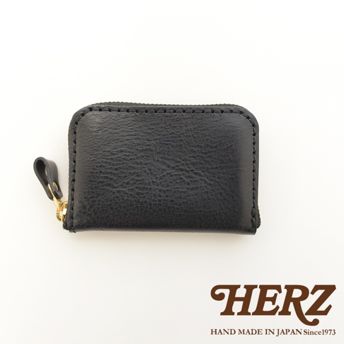 黑色皮革拉鍊錢包，簡約方形設計，配有金色拉鍊頭和皮革拉袢，展現職人手作質感。