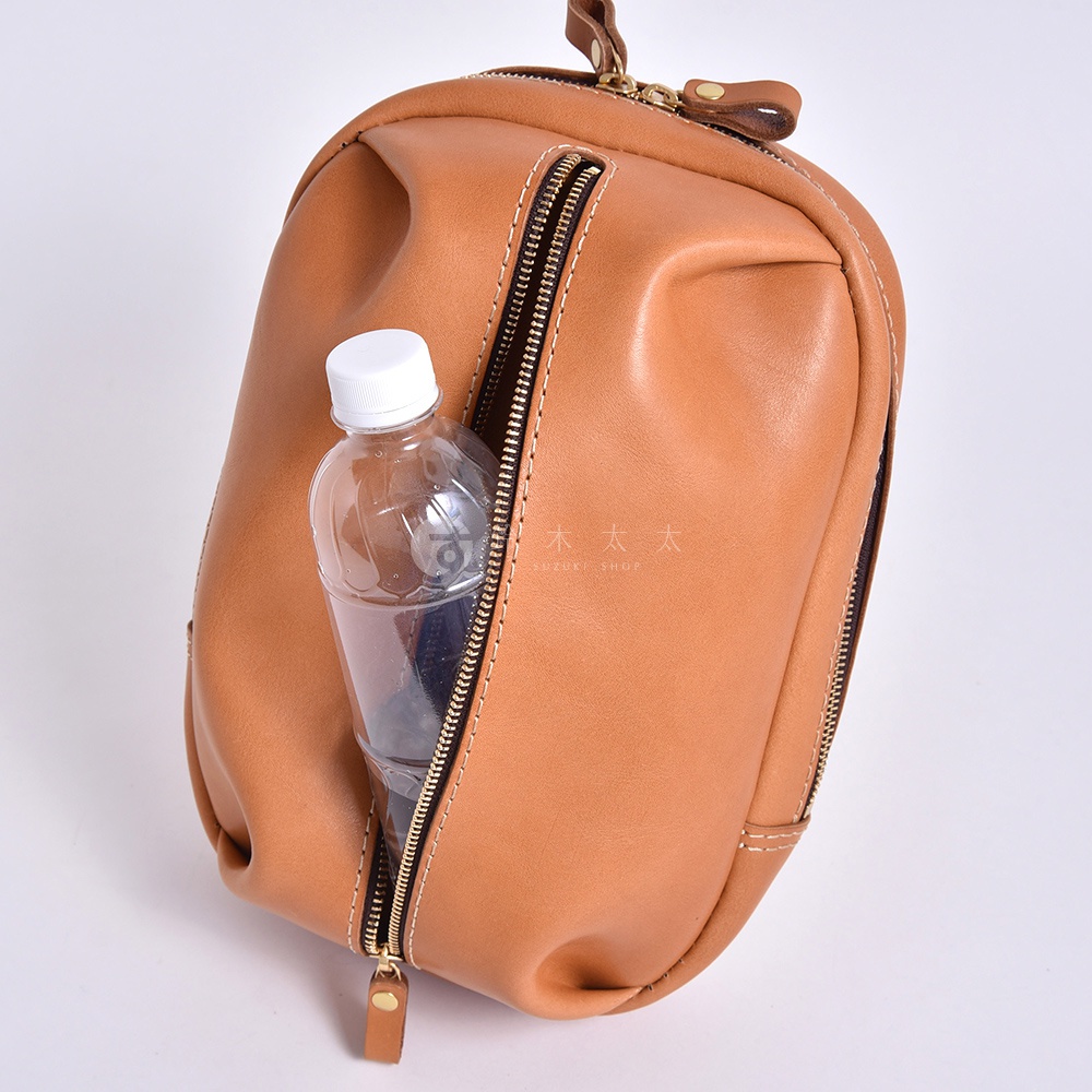 日本HERZ職人手作皮革立體運動斜背包 F-9，咖啡色Stare牛皮革，前側拉鍊袋內裝有一瓶寶特瓶。