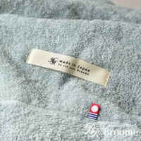 淺藍色今治毛巾被，觸感柔軟，帶有「made in Japan」和「La vie avec Broome」字樣的米白色標籤，以及一個帶有圓點和藍白條紋的紅色小標誌。
