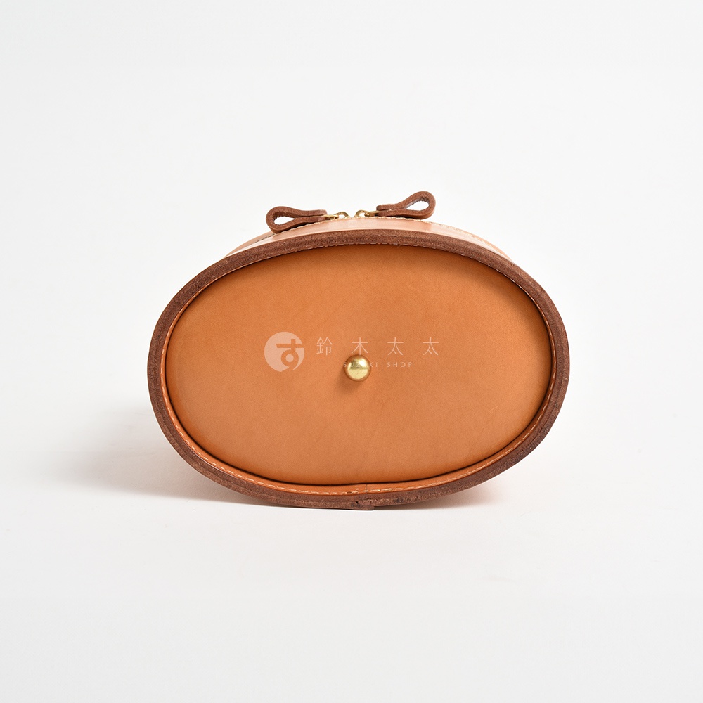 職人手作皮革圓筒型化妝手提包，淺棕色皮革，圓潤造型，頂部有皮革提把與拉鍊，中央有金色釦飾。