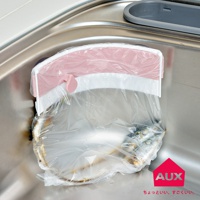 粉色與白色塑膠材質的開合式廚餘架，夾著塑膠袋，掛在不鏽鋼水槽邊緣，塑膠袋內有廚餘。