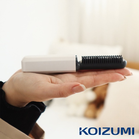 手持白色機身的黑色迷你瀏海梳，梳齒清晰可見