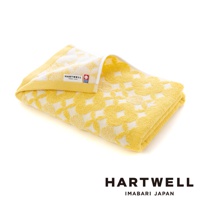 一條黃色毛巾，帶有白色傳統和風幾何紋樣，材質為棉，觸感柔軟。