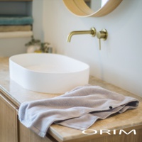 淺灰色毛巾，材質柔軟，上面有兩個扣子，放在洗手台的石材檯面上。