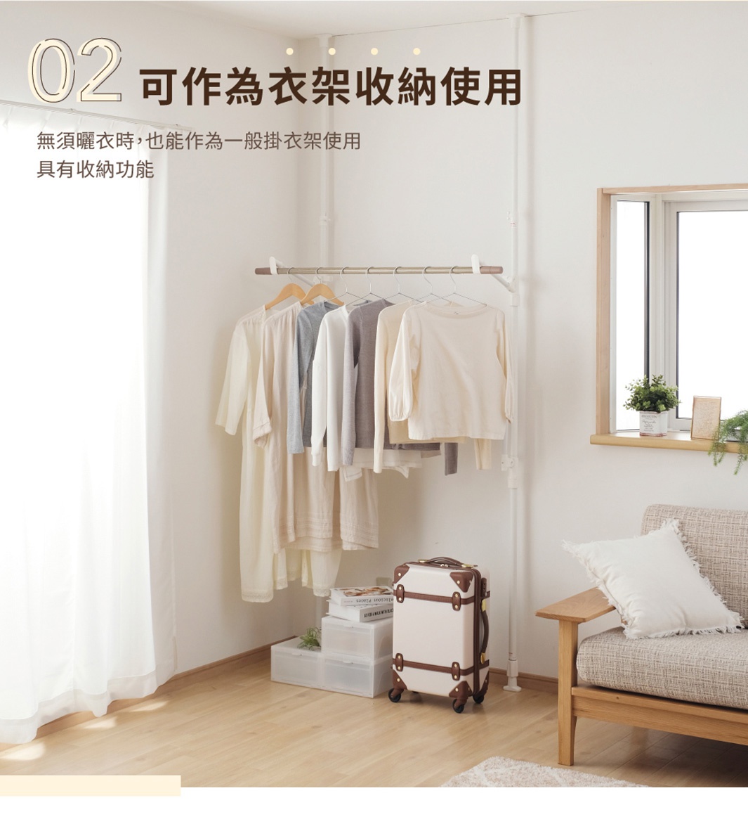 白色的頂天立地窗框曬衣架，帶有木紋飾邊，架上掛有數件淺色衣物，下方有透明收納箱和復古行李箱。