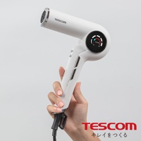 手持白色TESCOM離子吹風機，吹風機帶有LED顯示螢幕，顯示溫度和風力模式。