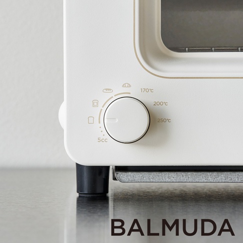 白色蒸氣烤麵包機的側面特寫，顯示操作旋鈕、溫度設定（170°C、200°C、250°C）以及圖示（吐司、麵包、水滴）。旋鈕為白色，有刻度指示。產品底部有黑色支腳和金屬質感的底座。