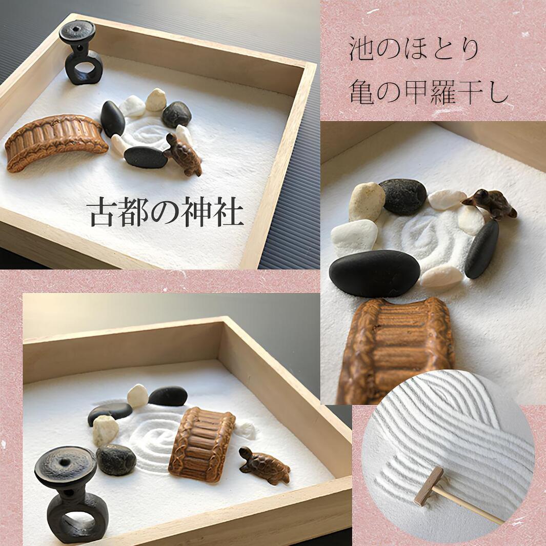 日式枯山水模型，木製砂盤內有白色細砂，擺放著黑色、灰色、白色鵝卵石，以及一座棕色仿木紋小橋、一隻龜造型擺飾和一個黑色石燈籠。