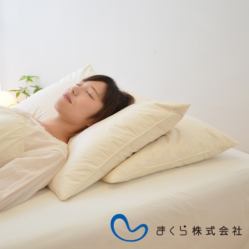 一女性側臥於雙層米白色羽絨枕上，枕頭材質柔軟蓬鬆，呈現飯店風格。