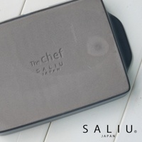 The chef 耐熱陶製萬用長方形烤盤 S，灰色平底，側面有黑色邊緣，烤盤底部印有「The chef」、「SALIU」及「JAPAN」字樣。