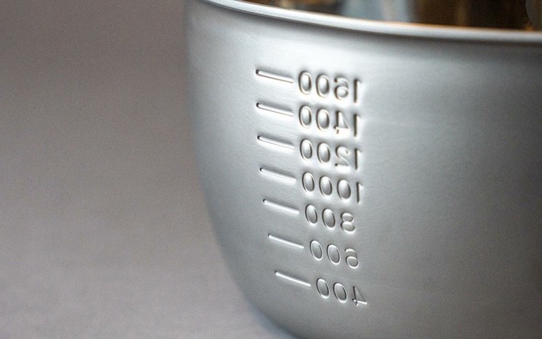 三層不鏽鋼雪平鍋的側面，刻有銀色字體的容量刻度，從 400ml 到 1800ml 不等，鍋身呈現細緻的霧面銀色。