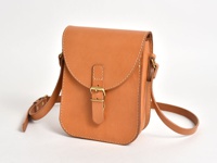 職人手作皮革翻蓋迷你單肩包，採用天然棕褐色皮革製成，帶有金屬釦和可調節肩帶，風格簡約復古。