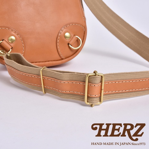 日本HERZ品牌皮革斜背包的細節，包含金屬釦環與帆布及皮革拼接的背帶