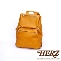 一個黃褐色皮革後背包，有頂部提把、兩個前置拉鍊口袋，以及側邊的扣帶和調整環。