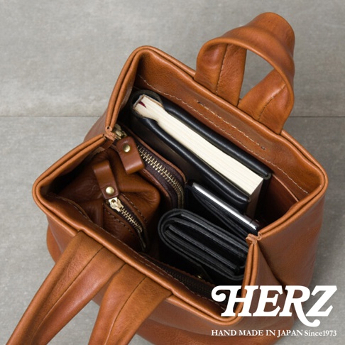 職人手作皮革Organ單柄手提包，棕色，包內裝有筆記本、錢包和化妝包，展現皮革質地與收納功能。