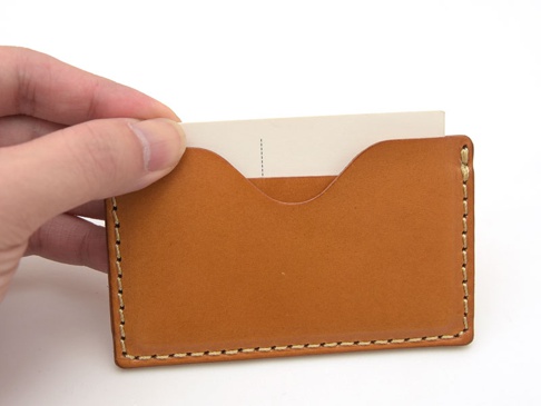 職人手作皮革卡片夾 (KV-47) N，由淺棕色皮革製成，邊緣以米白色縫線手工縫製，卡片夾頂部兩側有弧形開口，可放入白色卡片。