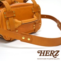 職人手作皮革大型三用旅行後背包，呈現自然棕色皮革，配有黃銅色金屬扣環和縫線，展現精緻工藝。