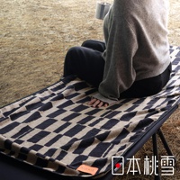 一位身穿灰色毛衣和黑色褲子的人坐在一張露營椅上，腿上鋪著一條帶有深藍色和米色格子圖案的毛巾，毛巾角落處有「HIORIE」標籤，右下角有「日本桃雪」的文字標記。