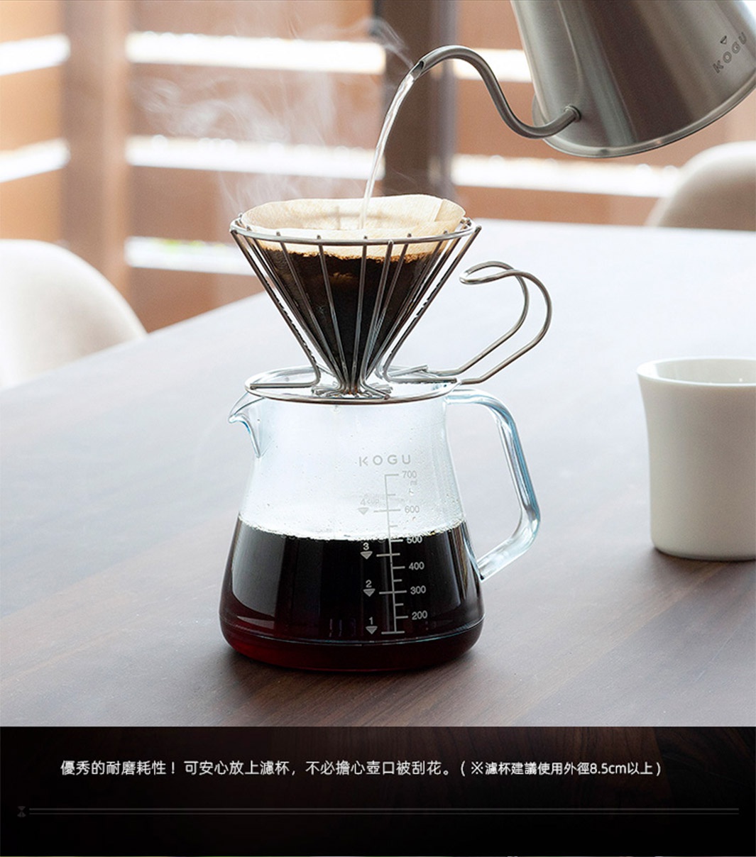日製Tritan材質700ml透明咖啡壺，壺身帶有白色刻度標示，盛有深棕色咖啡液。上方為金屬濾杯，濾杯內裝有咖啡粉，正有細長水流從金屬細嘴壺中注入。
