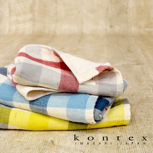 KONTEX 今治格紋雙織快乾毛巾，堆疊擺放，包含紅、藍、黃三種顏色，材質柔軟，背景為木紋紋理。