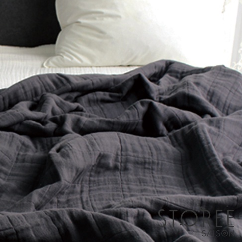 深灰色九層紗單人毯，材質輕暖，表面有格子紋理，鋪在床上，背景為白色床單和枕頭。