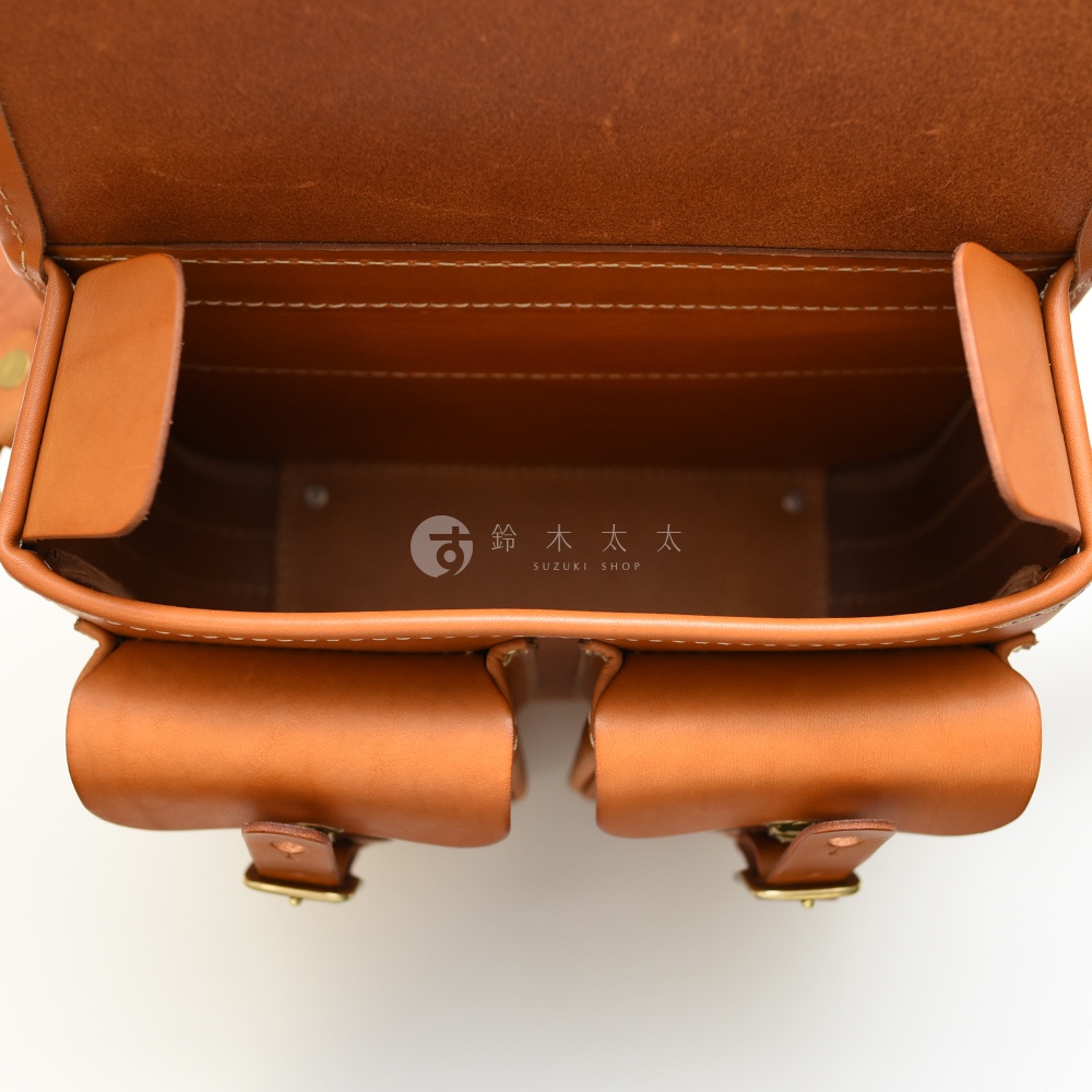 HERZ 經典雙扣郵差包內部，可見兩側皮革隔層與下方口袋，中央印有「鈴木太太 SUZUKI SHOP」的品牌標誌。