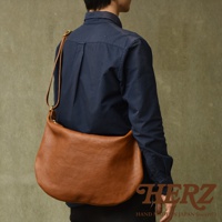 一位男士斜背一個棕色皮革製的半月形單肩包。