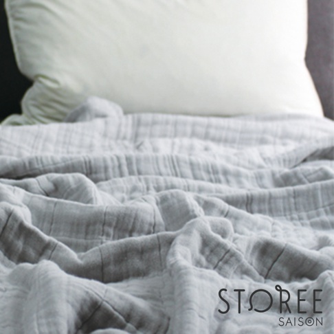 九層紗單人毯，呈現輕柔的淺灰色，布料有明顯的皺褶紋理，質地輕薄透氣。