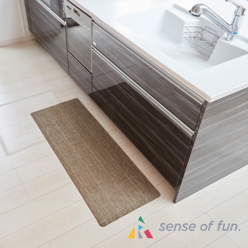 淺棕色可擦拭廚房地墊，織物材質，放在白色木紋地板上，旁邊是深棕色木紋櫥櫃和白色水槽。